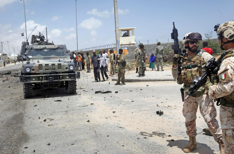 Two members of the Italian military, right, attend the scene after an attack on a European Union military convoy in the capital Mogadishu, Somalia Monday, Oct. 1, 2018. A Somali police officer says a suicide car bomber has targeted a European Union military convoy carrying Italian military trainers in the Somali capital Monday. (AP Photo/Farah Abdi Warsameh)