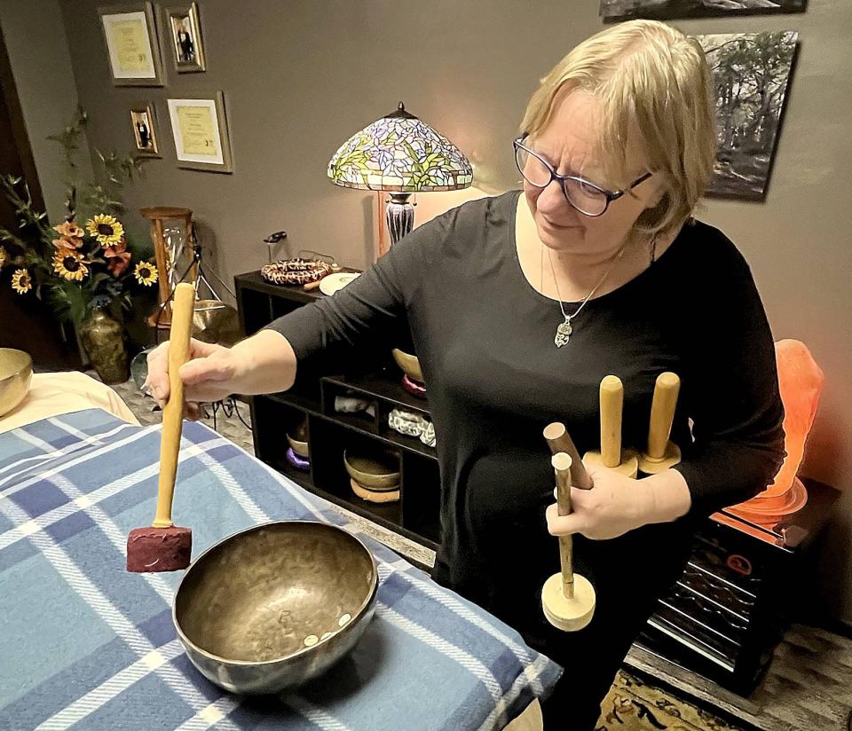 Gale Simon, owner of Acoustic Therapy Partners in Erie, demonstrates the sounds different mallets make when they come in contact with a therapeutic bowl on Jan. 4, 2023.