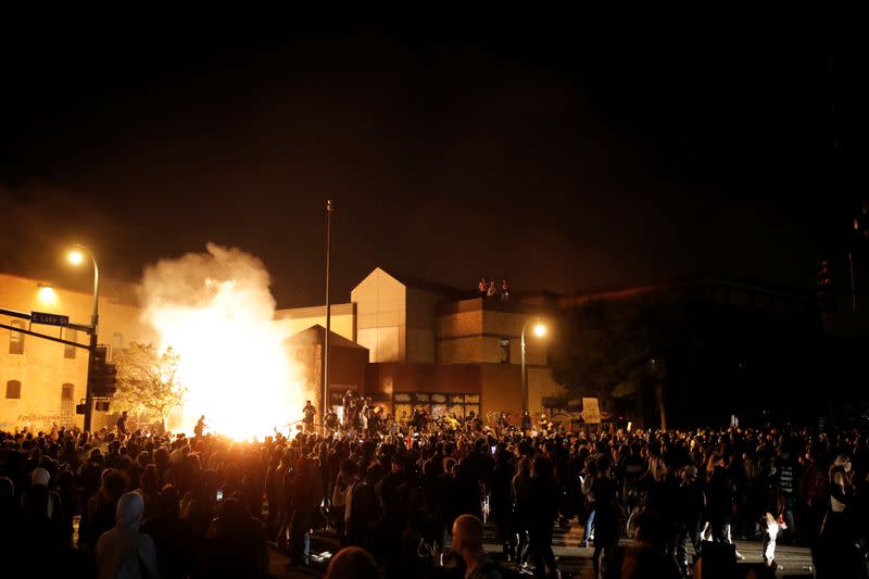 Protesters gather around after setting fire to the entrance of a police station as demonstrations continue in Minneapolis