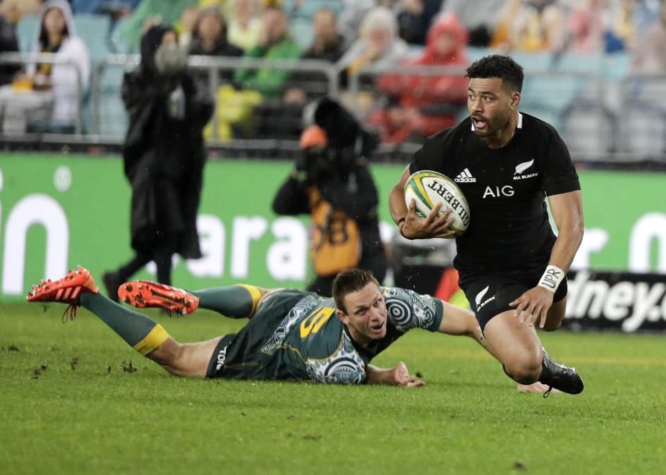 New Zealand's Richie Mo'unga falls as he looks for support as Australia's Dane Haylett-Petty, left, watches during the Bledisloe rugby test between the All Blacks and the Wallabies at Stadium Australia, Sydney, Australia, Saturday, Oct. 31, 2020. (AP Photo/Rick Rycroft)