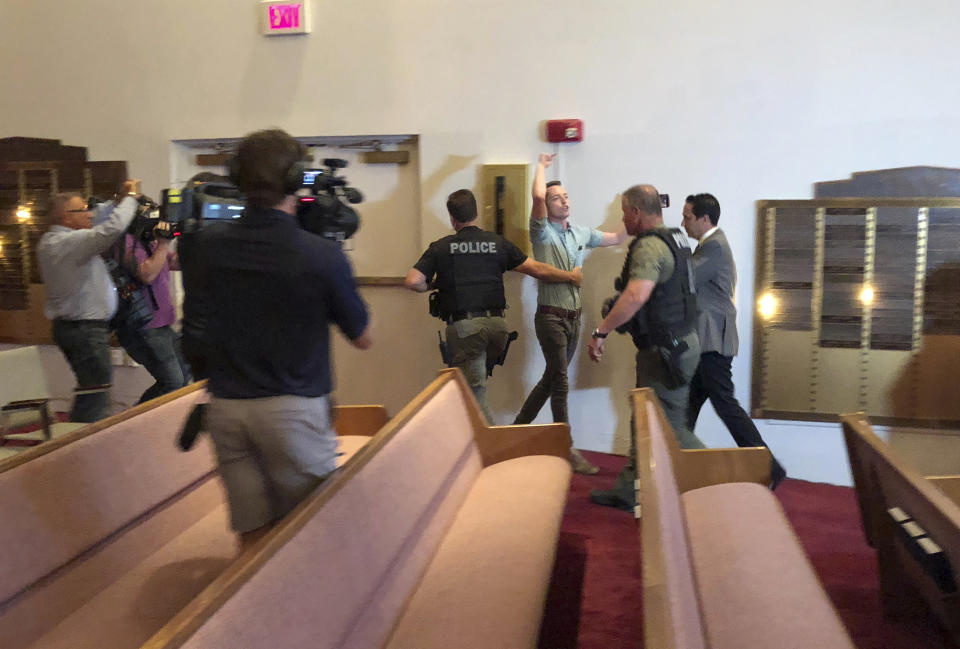 Police officers escort protester Jacob Engels from a Florida synagogue Thursday, Oct. 25, 2018, in Plantation, Fla., before a speech by Democratic gubernatorial candidate Andrew Gillum. Engel shouted Gillum is "a radical Jew hater who supports mob violence" as he was removed by Plantation, Florida, police officers. Gillum later told the crowd that support for Israel should be bipartisan and that accusations he is an anti-Semite are false. (AP Photo/Terry Spencer)