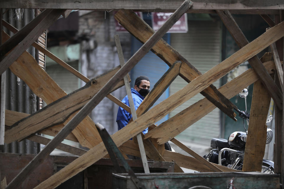 A Kashmiri volunteer looks through temporary barricades erected to prevent outsiders from entering an area declared as red zone by the government during lockdown in Srinagar, Indian controlled Kashmir, on April 14, 2020. | Mukhtar Khan—AP