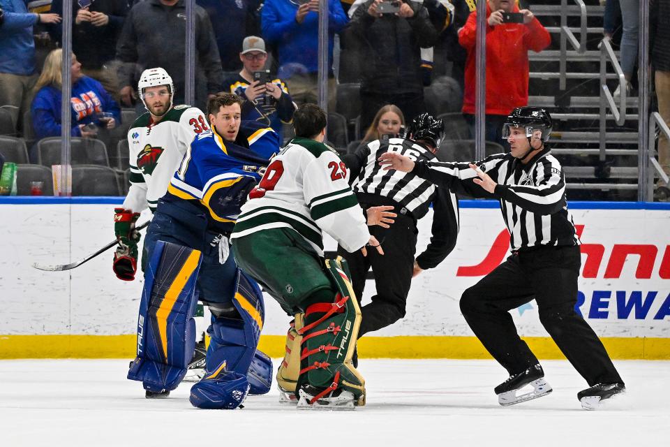 St.  Louis Blues goaltender Jordan Binnington (50) and Minnesota Wild goaltender Marc-Andre Fleury (29) are separated by linesmen before they can fight.