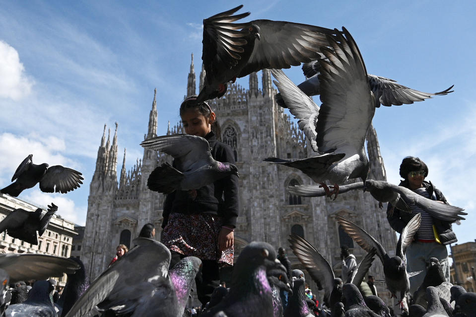 A girl plays with pigeons at Piazza del Duomo in Milan, on March 29, 2023.