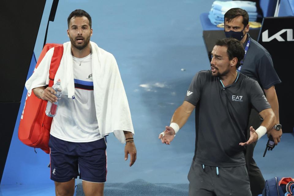 Italy's Fabio Fognini, right, speaks as compatriot Salvatore Caruso walks away after their second round match at the Australian Open tennis championship in Melbourne, Australia, Thursday, Feb. 11, 2021. Fognini won the match. (AP Photo/Hamish Blair)