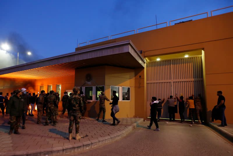 Protesters and militia fighters gather to condemn air strikes on bases belonging to Hashd al-Shaabi (paramilitary forces), outside the main gate of the U.S. Embassy in Baghdad