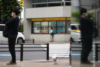 A man waits for the traffic light to turn standing by monitors showing Japan's Nikkei 225 index at a securities firm in Tokyo, Thursday, June 13, 2024. (AP Photo/Hiro Komae)