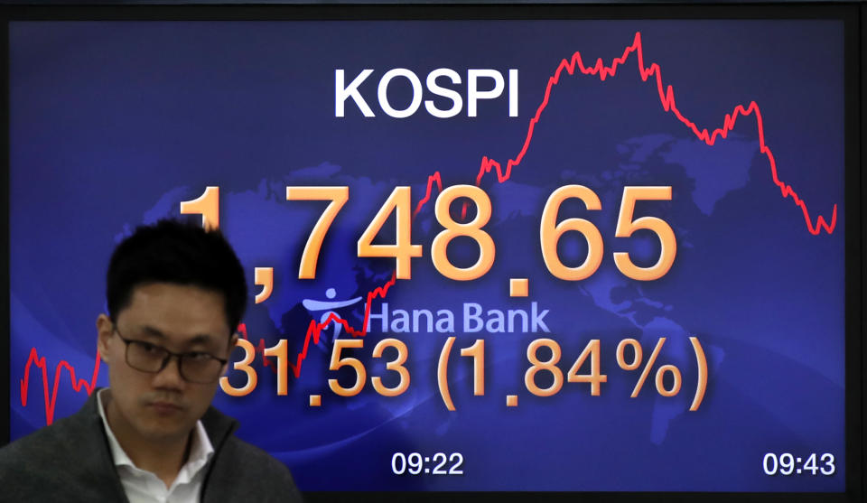 A currency trader walks by the screen showing the Korea Composite Stock Price Index (KOSPI) at the foreign exchange dealing room in Seoul, South Korea, Tuesday, March 31, 2020. Asian shares surged Tuesday after a rally in U.S. stocks, mostly spurred by health care companies' announcements of developments that could aid in the coronavirus outbreak.(AP Photo/Lee Jin-man)