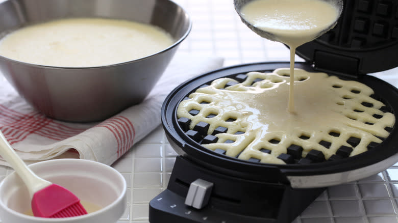 waffle batter poured into griddle next to bowl on counter