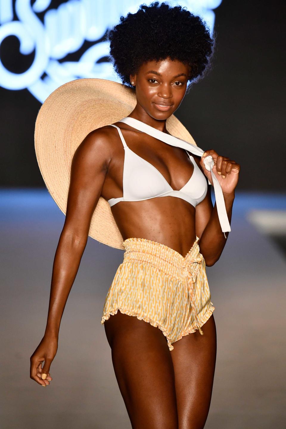 <p>A model walks the runway in a white bikini top, shorts, and an oversize sun hat for the swimsuit show during the Paraiso Fashion Fair in Miami at the W South Beach hotel on July 15. (Photo: Alexander Tamargo/Getty Images for Sports Illustrated) </p>