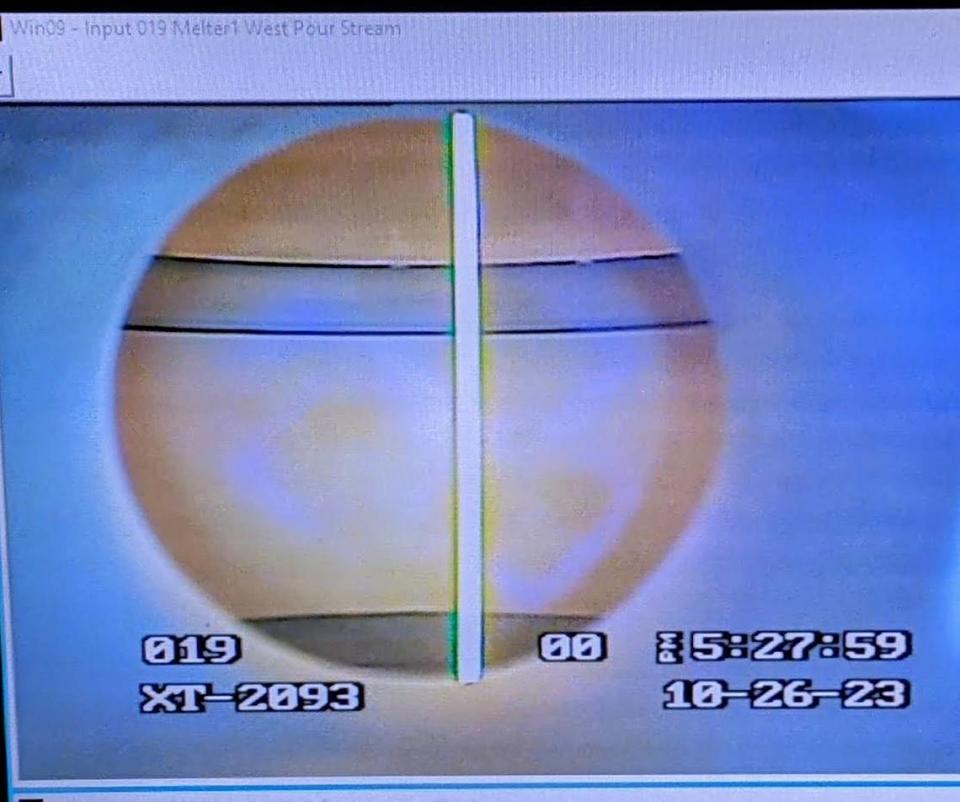 A monitor shows a stream of molten glass being poured.