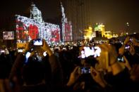 Visitors take pictures and videos during a light show as part of a New Year countdown celebration as part of a New Year countdown celebration on the Bund in Shanghai January 1, 2014. REUTERS/Aly Song