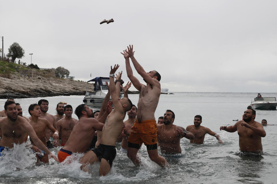 Pilgrims jump to catch the cross during a water blessing ceremony marking the Epiphany celebrations at Piraeus suburb, near Athens, on Monday, Jan. 6, 2020. Similar ceremonies marking Epiphany were held across Greece on river banks, seafronts and lakes, where Orthodox priests throw a cross into the water and swimmers race to retrieve it. (AP Photo/Thanassis Stavrakis)