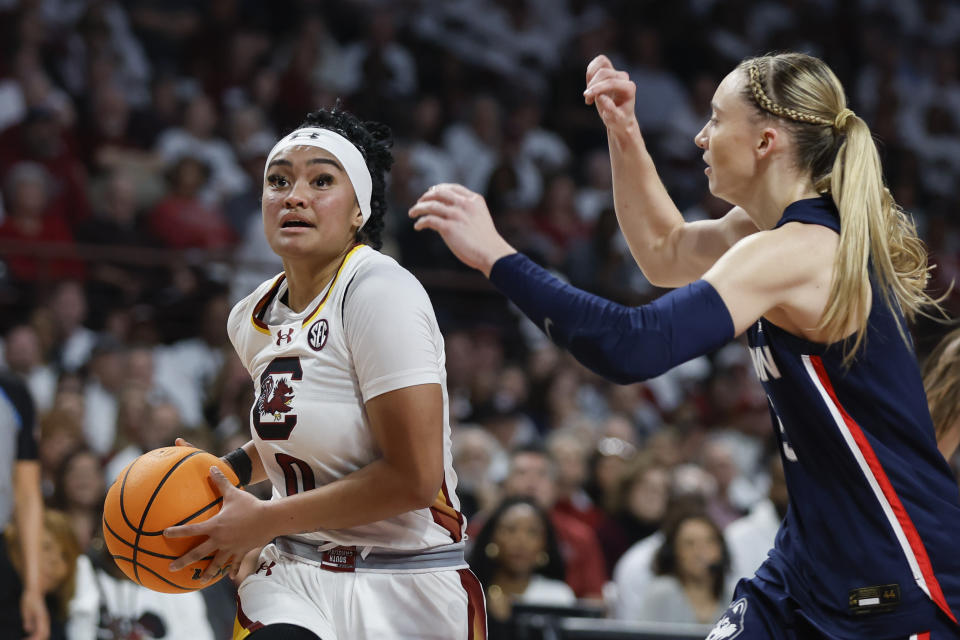 South Carolina guard Te-Hina Paopao, left, drives to the basket against UConn guard Paige Bueckers, right, during the first half of an NCAA college basketball game in Columbia, S.C., Sunday, Feb. 11, 2024. (AP Photo/Nell Redmond)