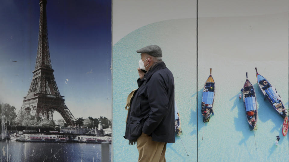 A ma wearing a face mask walks by a closed travel agency in Lisbon, Wednesday, Jan. 27, 2021. Portugal has had the world's worst rate of new daily cases and deaths per 100,000 population for the past week, according to a tally by Johns Hopkins University. (AP Photo/Armando Franca)