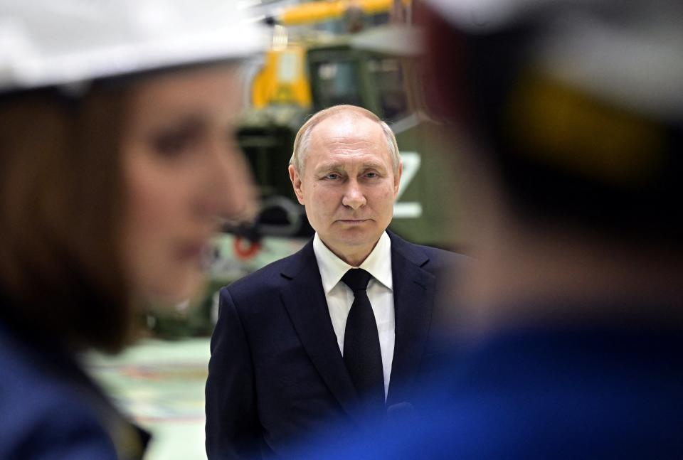 Putin with workers at the factory in Saint Petersburg today (Reuters)