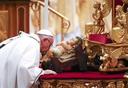 Pope Francis kisses a statue of baby Jesus as he leads the Christmas night Mass in Saint Peter's Basilica at the Vatican December 24, 2016. REUTERS/Tony Gentile