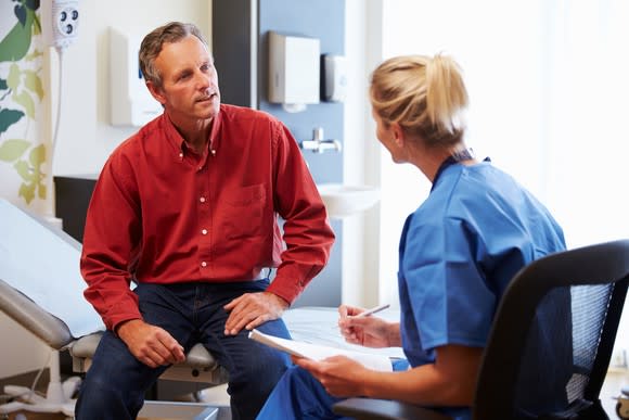 Female doctor talking with male patient in an exam room