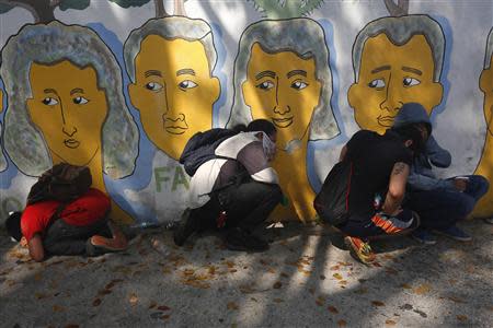 Anti-government protesters take cover from tear gas launched by police during a protest in Caracas March 12, 2014. REUTERS/Tomas Bravo