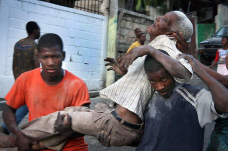 An injured man is carried by survivors of a magnitude-7 earthquake in Port-au-Prince, Haiti, on January 13, 2010. File Photo by Matthew Marek/American Red Cross