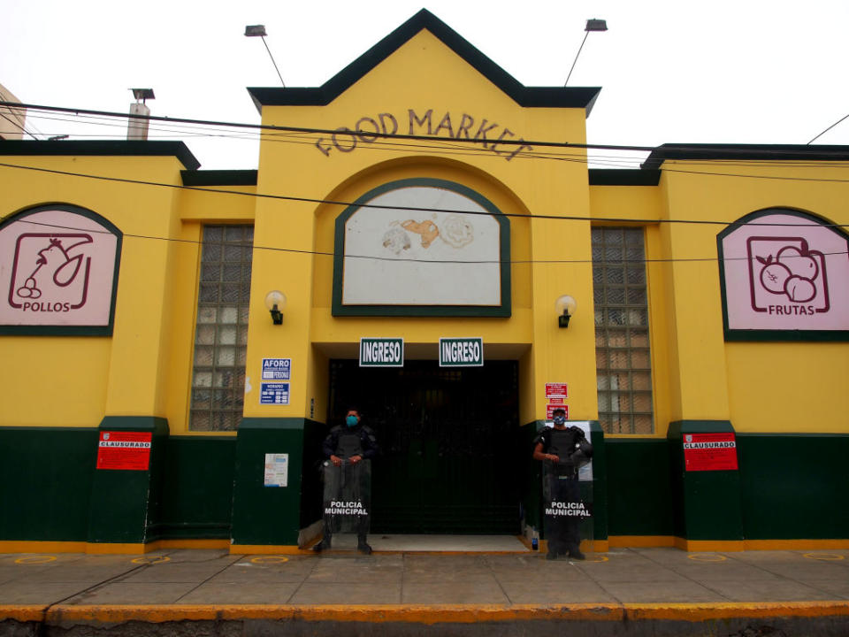 Municipal police guard the doors of a food market closed for sanitary measures, due to Covid-19, in a neighborhood of the Lima on May 27. | Carlos Garcia Granthon– Fotoholica Press/LightRocket/Getty Images