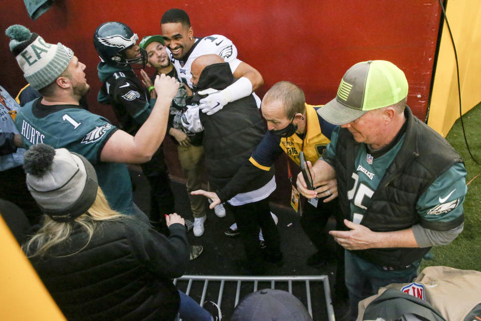 Fans fall on Philadelphia Eagles quarterback Jalen Hurts (1) after beating the Washington Football Team 20-16 on Sunday, January 2, 2022 in Landover, Maryland.(Shaban Athuman/Richmond Times-Dispatch via AP)