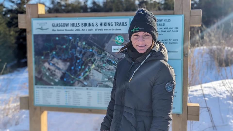 Jessica Corbett of the Central Region Sport and Recreation Council stands next to the trail map at Glasgow Hills. 