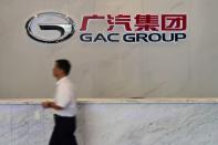 Man walks past the logo of Chinese automobile maker GAC Group at the company headquarters in Guangzhou