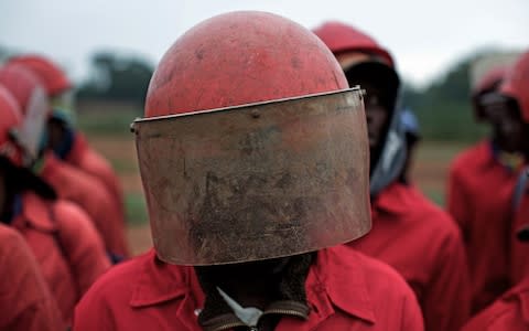 The Red Ants, in their trademark red overalls and helmets, line up in military formation before an operation, on February 9, 2017 - Credit:  James Oatway