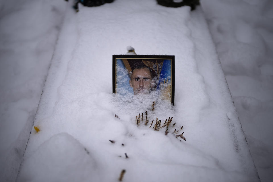 A portrait of Sgt. Mykhaylovych Shchrman, 42, partially-covered by snow, sits on his grave at a cemetery in Lviv, Ukraine, Tuesday, Feb. 7, 2023. He was killed on April 7, 2022. (AP Photo/Emilio Morenatti)