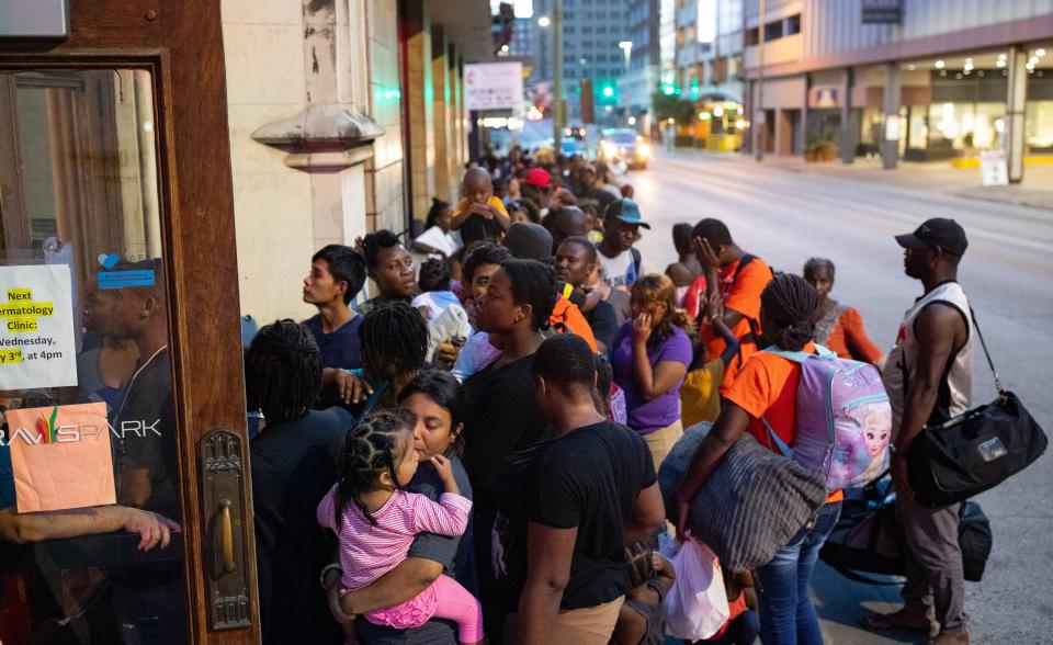 SAN ANTONIO, Texas – Delmy López, 31, de Honduras, lleva en brazos a su hija de dos años, Perla, mientras esperan en fila para entrar el refugio nocturno para migrantes de la Iglesia Metodista Unida de Travis Park el 27 de junio del 2019.