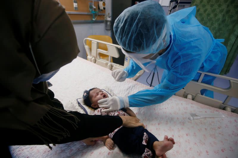 A medical team member takes a swab sample from a child who suffers from cancer to test for the coronavirus disease (COVID-19) in Basra