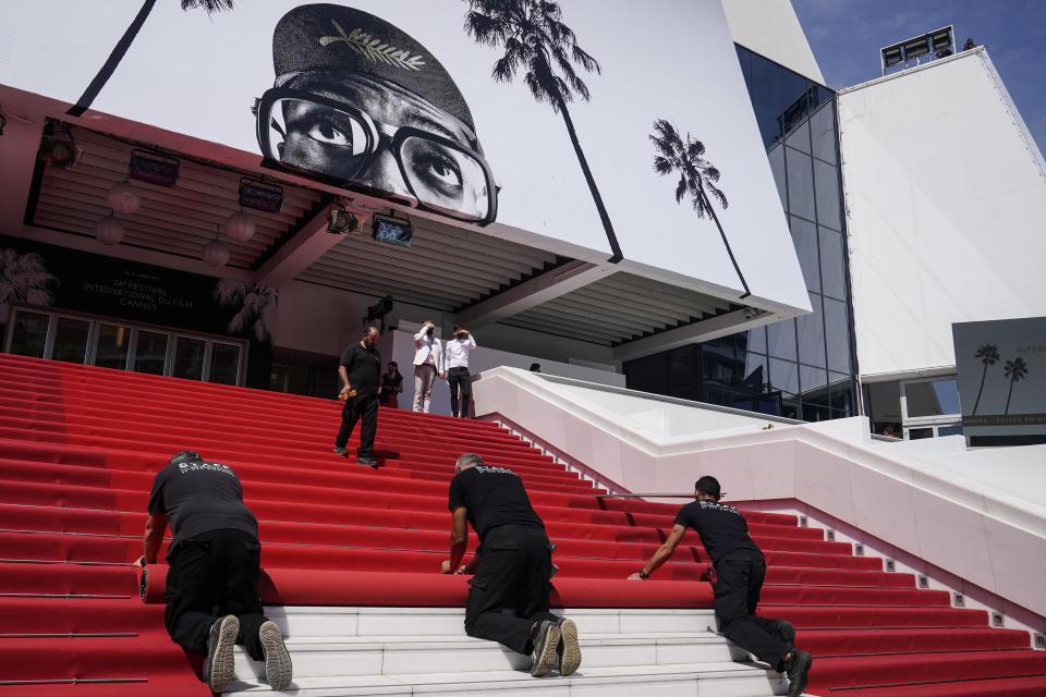 FILE - In this July 6, 2021 file photo Crew members install the red carpet at the Palais des Festival ahead of the opening day of the 74th international film festival, Cannes, southern France. The Cannes Film Festival returned this month, rolling out the red carpet and restoring glamour to the French Riviera with a collection of provocative films and a parade of stars. (AP Photo/Brynn Anderson, File)