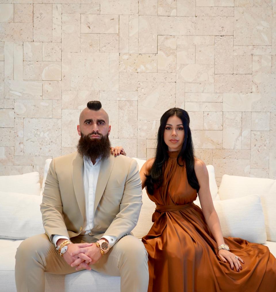 A man and woman posing on a white couch.