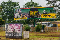 <p>A woman in military uniform walks past a billboard with a poster of ruling party Zimbabwe African National Union – Patriotic Front (Zanu PF) and a picture of President Robert Mugabe in Harare on Nov. 15, 2017. (Photo: AFP/Getty Images) </p>