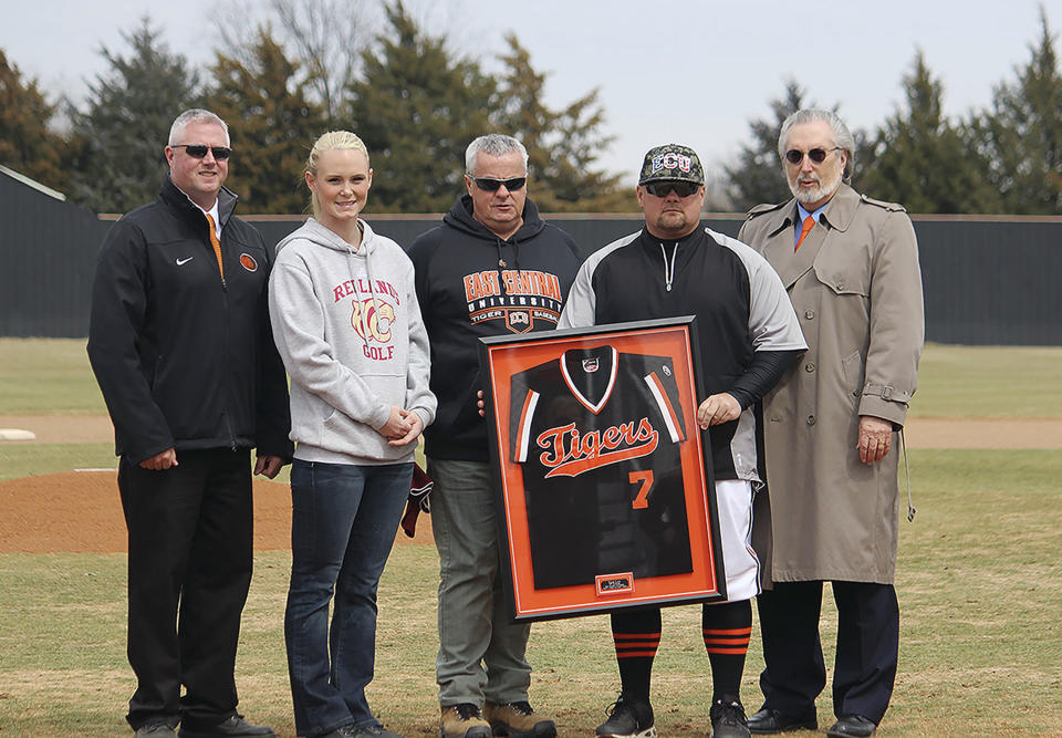 In this March 5, 2014 photo provided by East Central University, ECU director of athletics Jeff Williams, from left, Sarah Harper, Lane’s girlfriend, Peter Lane, Chris Lane’s father, ECU head baseball coach Dino Rosato and ECU Provost and vice president for academic affairs Duane Anderson pose for a photo during a ceremony to retire Australian native Chris Lane’s jersey at East Central University in Ada, Okla. Twenty-two-year Lane, of Melbourne, Australia, was preparing to enter his senior season at East Central University when he was gunned down last August. Lane’s death has left a void for his college team. (AP Photo/East Central University)