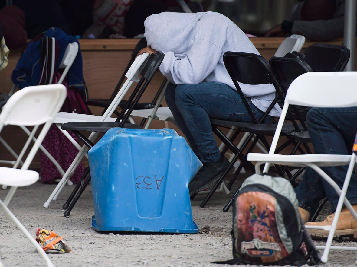 An asylum seeker rests his head at a makeshift processing centre at the Canada-United States border on Roxham Road in Hemmingford, Que., on Aug. 9, 2017.  (Graham Hughes/The Canadian Press - image credit)