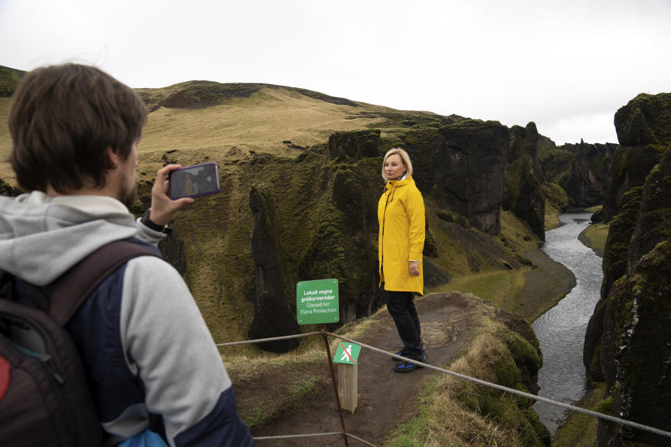 In this photo taken Wednesday, May 1, 2019, Russian tourist Nadia Kazachenok poses for a photograph taken by Mikhail Samarin at the Fjadrárgljúfur. The canyon is closed, with roadblocks and rope fences, but tourists were quick to pass when the ranger went off duty on a Wednesday afternoon. (AP photo/Egill Bjarnason)