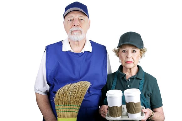 Senior man and woman wearing work clothes and unhappy expressions.