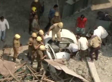 Rescue workers attempt to rescue a person trapped in a car after a flyover collapsed, in Kolkata
