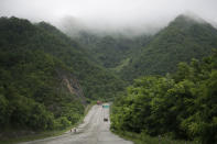 <p>Two men are dwarfed by a mountainous backdrop as they sweep rainwater off the Pyongyang-Wonsan highway on July 22, 2017, in North Korea. The Pyongyang-Wonsan highway is 172-kilometer-long or 107 miles long and it connects the North Korean capital to Wonsan, a port city on the Korean Peninsula. (Photo: Wong Maye-E/AP) </p>