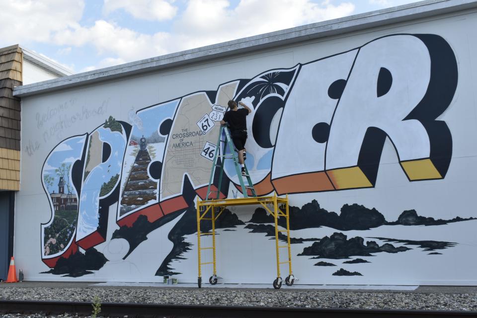 Israel Hogan continues work on a mural in Spencer.