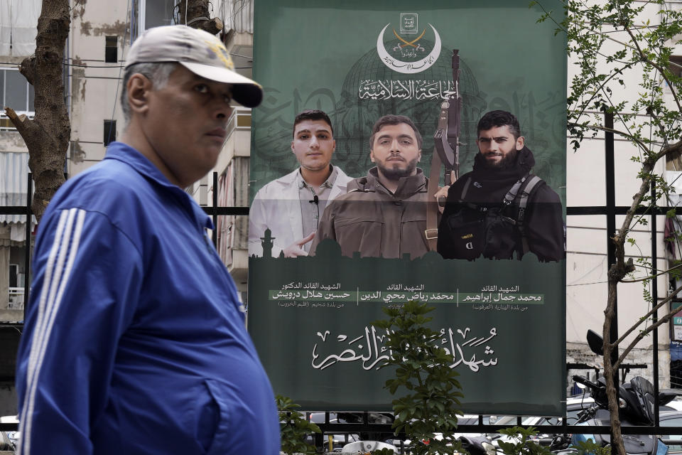 A man passes by a poster showing Islamic Group members known as Jamaa Islamiya, who were killed two weeks ago in an Israeli strike, in Beirut, Lebanon, Tuesday, March 26, 2024. The Secretary-General of al-Jamaa al-Islamiya, or the Islamic Group, Sheikh Mohammed Takkoush allied with Hamas and Hezbollah said Tuesday they are closely coordinating with both groups along the southern border with Israel where they have claimed responsibility for several attacks over the past months. (AP Photo/Bilal Hussein)