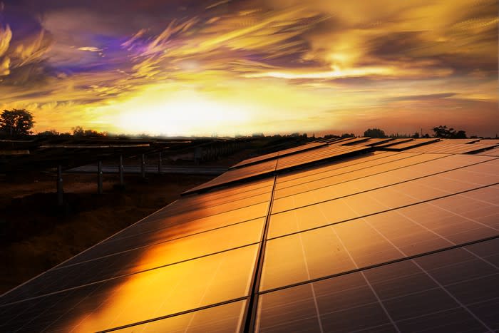 Solar panels on a rooftop with the sun setting in the background.