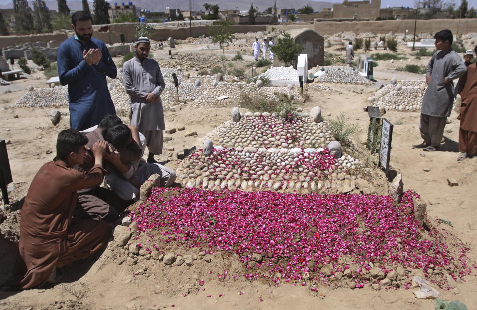 People comfort each-other at the grave of their family member who was killed in the Wednesday's bomb blast at a luxury hotel in Quetta, Pakistan, Thursday, April 22, 2021. An attack at a luxury hotel in Pakistan has been confirmed as a suicide car bombing, and the death toll has risen to five, police said Thursday. (AP Photo/Arshad Butt)