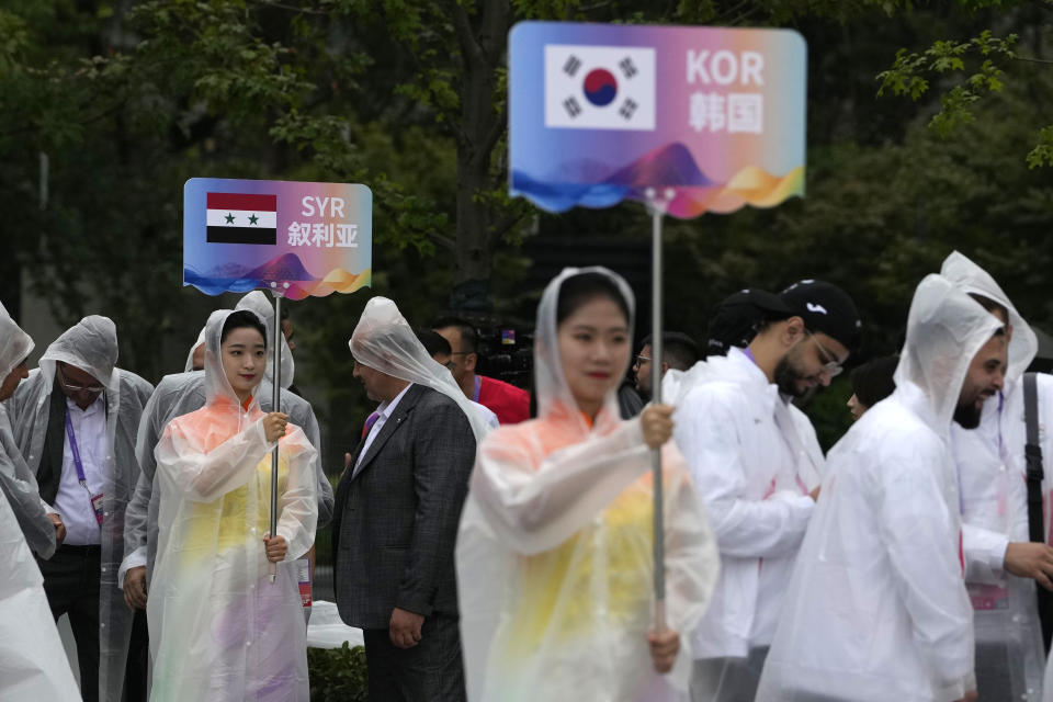 Volunteers hold country signs during team welcoming ceremony at the 19th Asian Games in Hangzhou, China, Thursday, Sept. 21, 2023. The Asian Games are an attention grabber. For starters, they involve more participants than the Summer Olympics. Organizers say more than 12,000 will be entered as the opening ceremony takes place Saturday, Sept. 23 in the eastern Chinese city of Hangzhou. (AP Photo/Ng Han Guan)