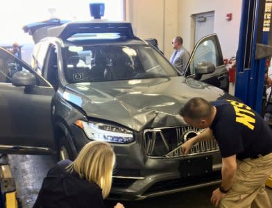 FILE PHOTO: U.S. National Transportation Safety Board (NTSB) investigators examine a self-driving Uber vehicle involved in a fatal accident in Tempe, Arizona, U.S., March 20, 2018.  A women was struck and killed by the vehicle on March 18, 2018.     National Transportation Safety Board/Handout via REUTERS/File Photo