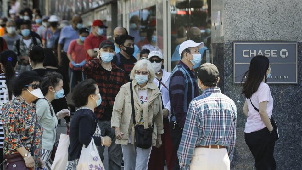 Menschen mit Masken warten im New Yorker Stadtbezirk Queens vor dem Eingang einer Bank.