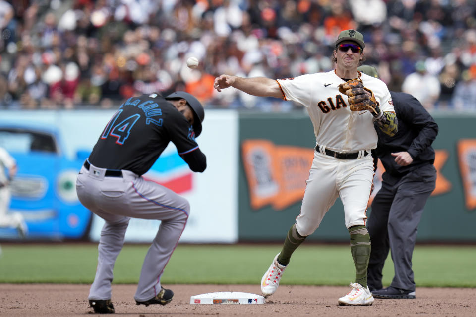 Miami Marlins' Bryan De La Cruz, left, ducks as San Francisco Giants shortstop Casey Schmitt, front right, turns a double play against Marlins' Joey Wendle (not shown) during the fourth inning of a baseball game in San Francisco, Saturday, May 20, 2023. (AP Photo/Godofredo A. Vásquez)