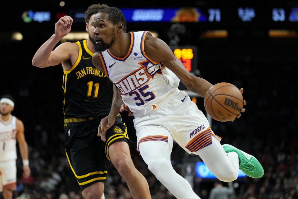 Phoenix Suns forward Kevin Durant (35) drives as Golden State Warriors guard Klay Thompson (11) defends during the second half of an NBA basketball game, Wednesday, Nov. 22, 2023, in Phoenix. (AP Photo/Matt York)